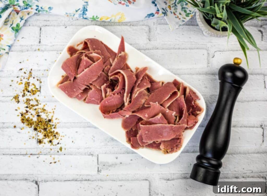 A top-down shot of sliced corned beef on a white platter.