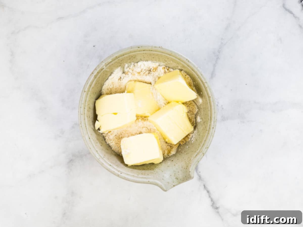 A small bowl containing butter, brown sugar, and flour being mixed with a fork to form a crumbly topping for the tarts.