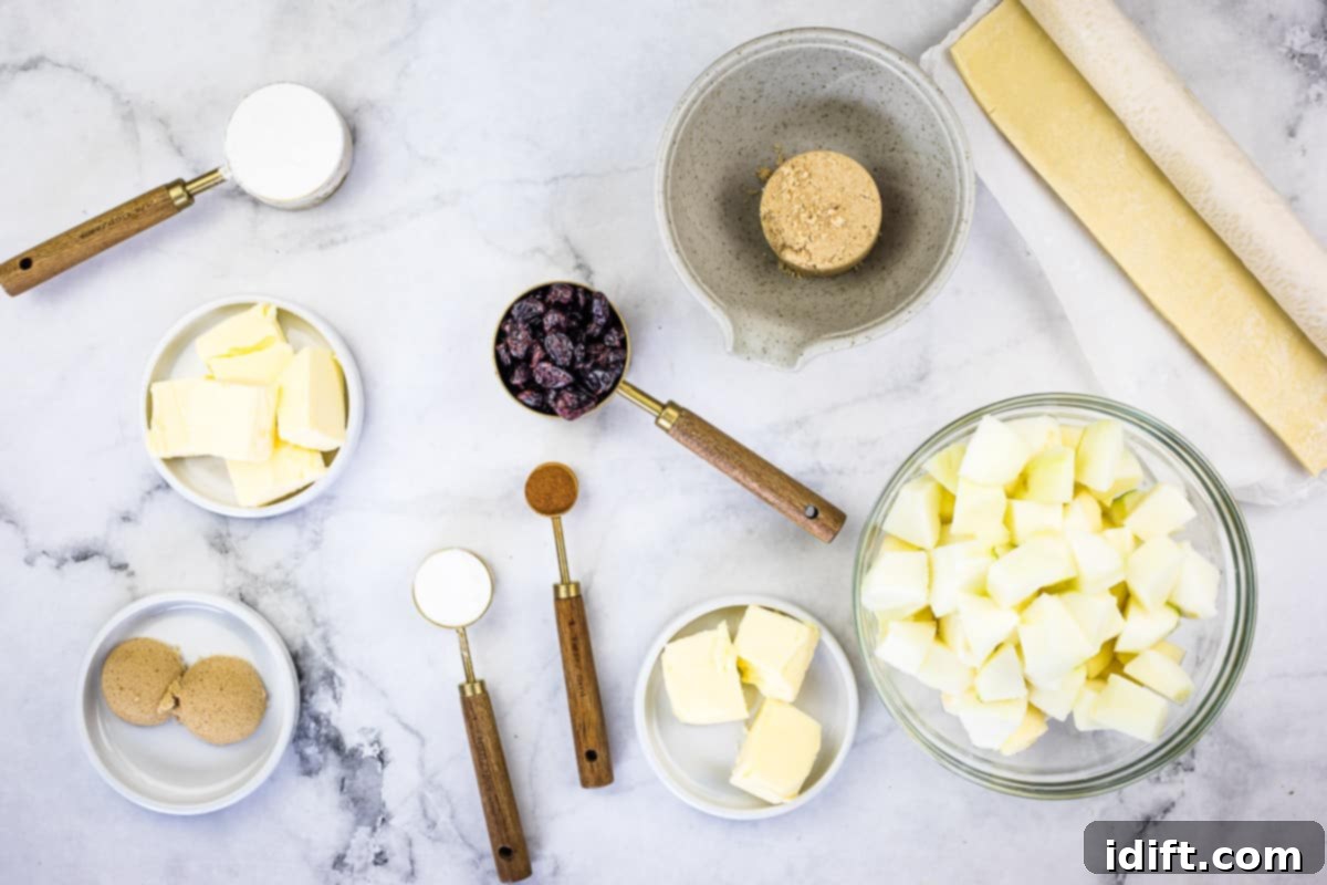 All the fresh ingredients for apple-cranberry puff pastry tarts neatly laid out on a kitchen counter, including diced apples, butter, sugar, and spices.