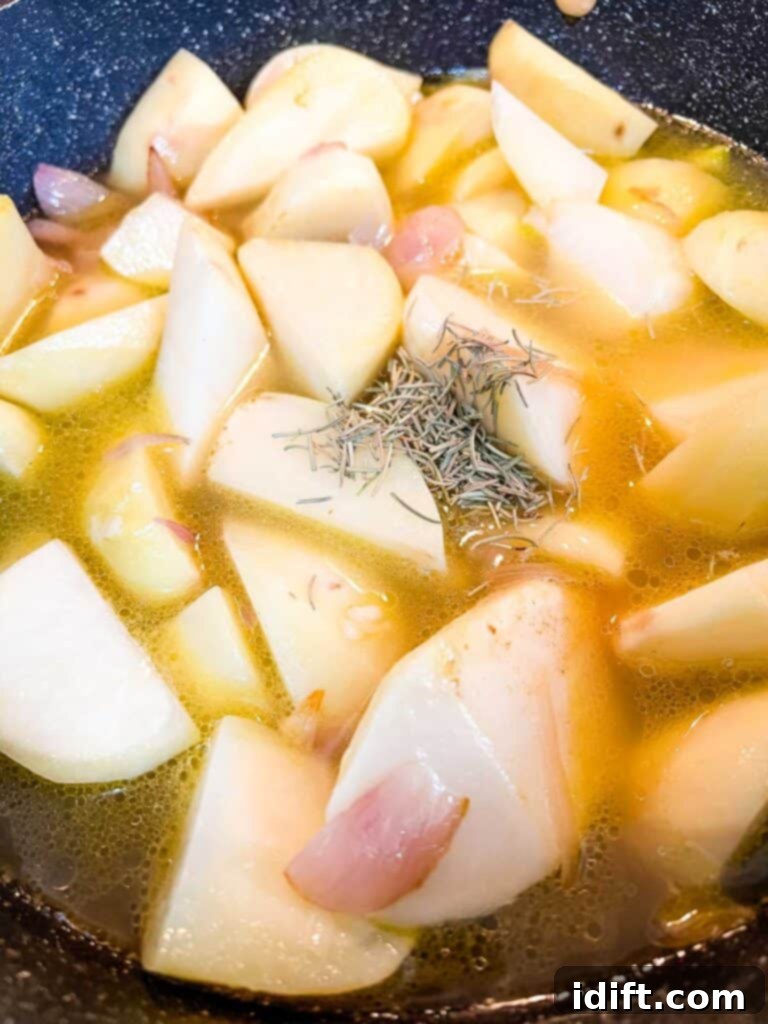 Rustic Rosemary Garlic Potato Braise 8 Chicken broth, rosemary, salt, and pepper added to browned potatoes and shallots in a skillet.