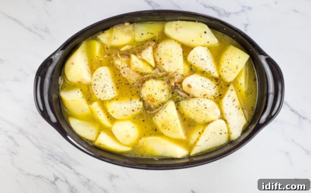 Rustic Rosemary Garlic Potato Braise 9 Potatoes and braising liquid transferred into an oven-safe casserole dish, covered and ready for the oven.