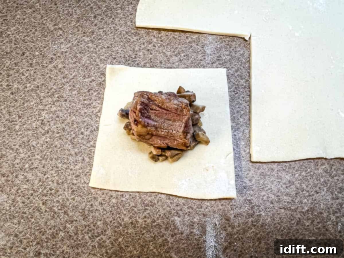 A square of puff pastry topped with the mushroom mixture and a cube of beef.