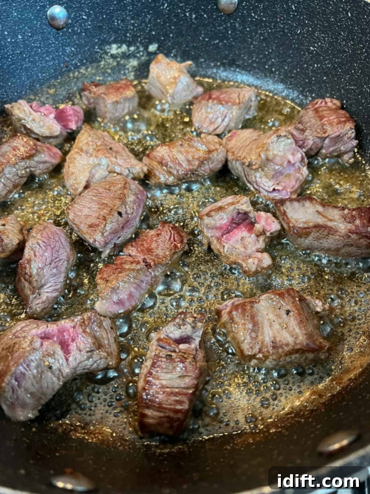 Browning the seasoned beef in butter and oil.