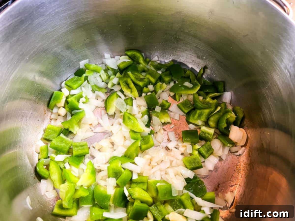 Onions, bell pepper and garlic cooking in a pot.