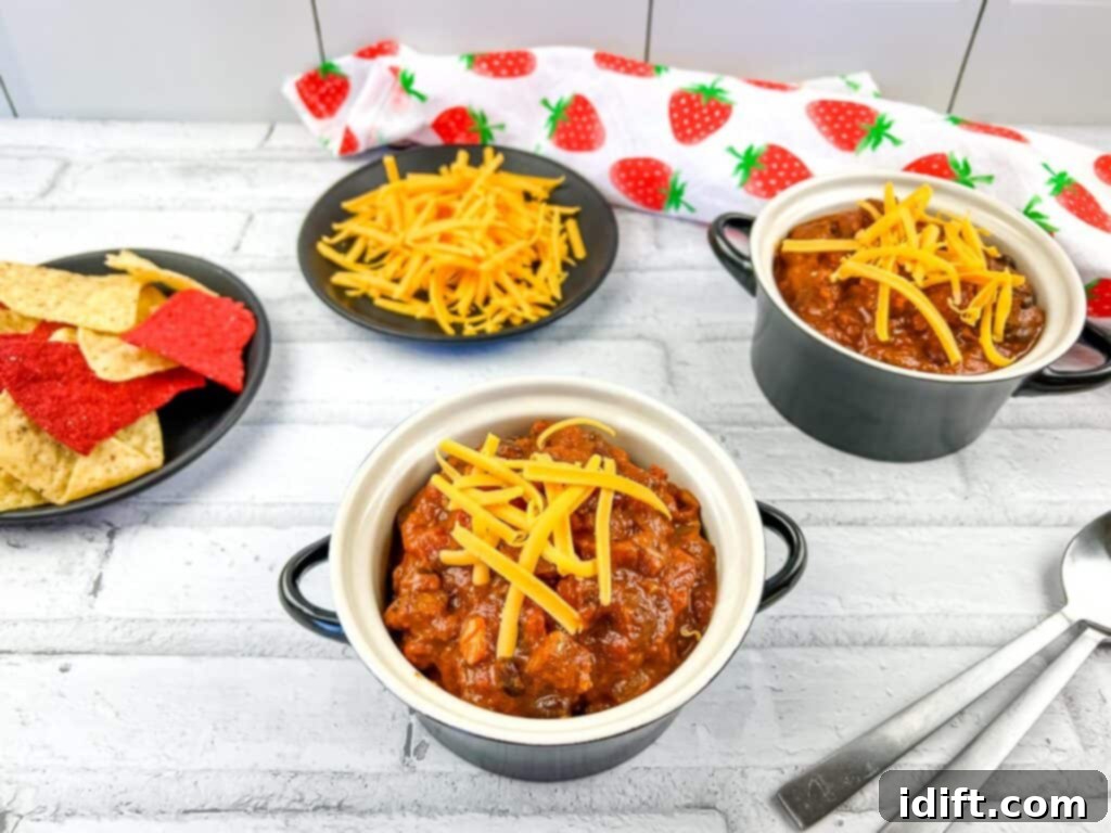 2 bowls of Smoked Brisket Chili on a table with tortilla chips in the background.