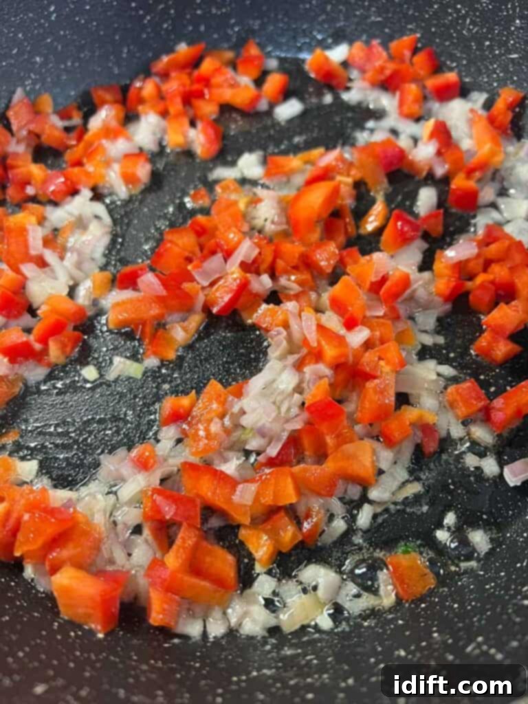 Red bell pepper added to the shallots in a skillet.