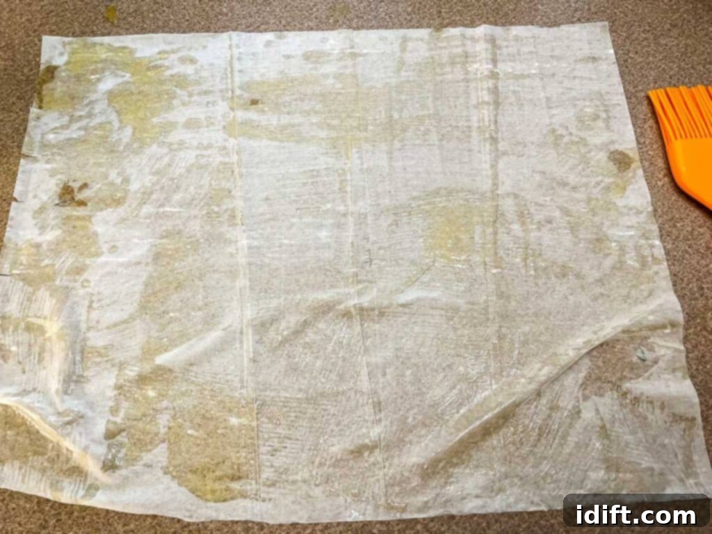 One sheet of phyllo on a coutertop with butter on it.