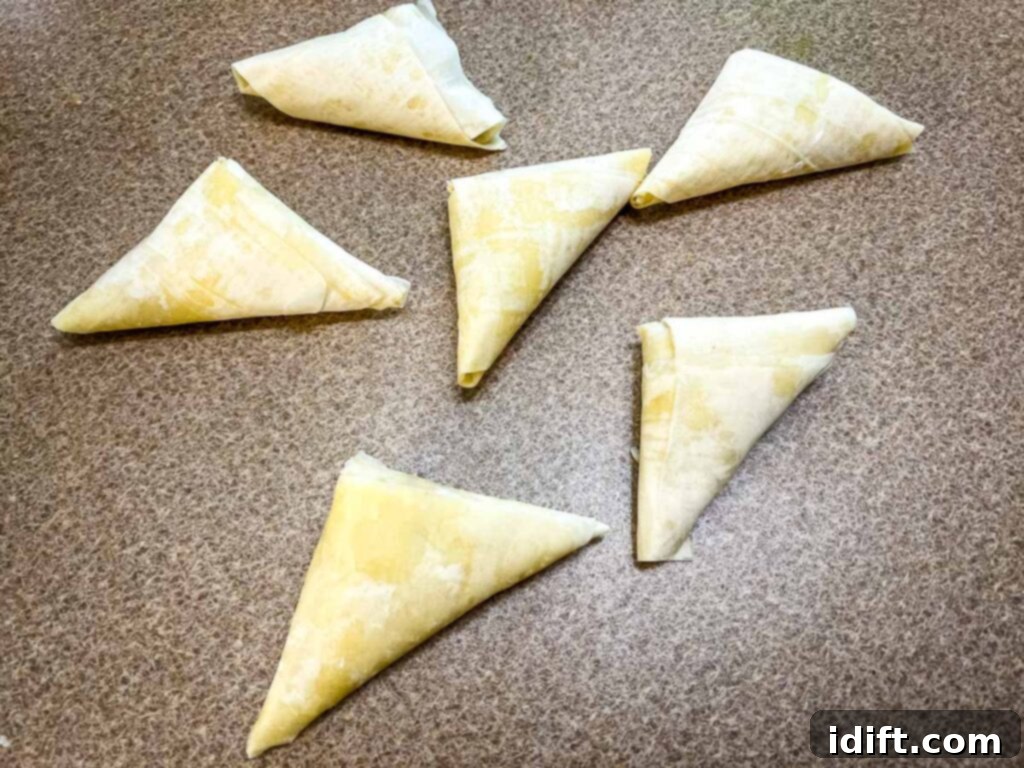 Butter the tops of the Crab Spanakopita triangles. 