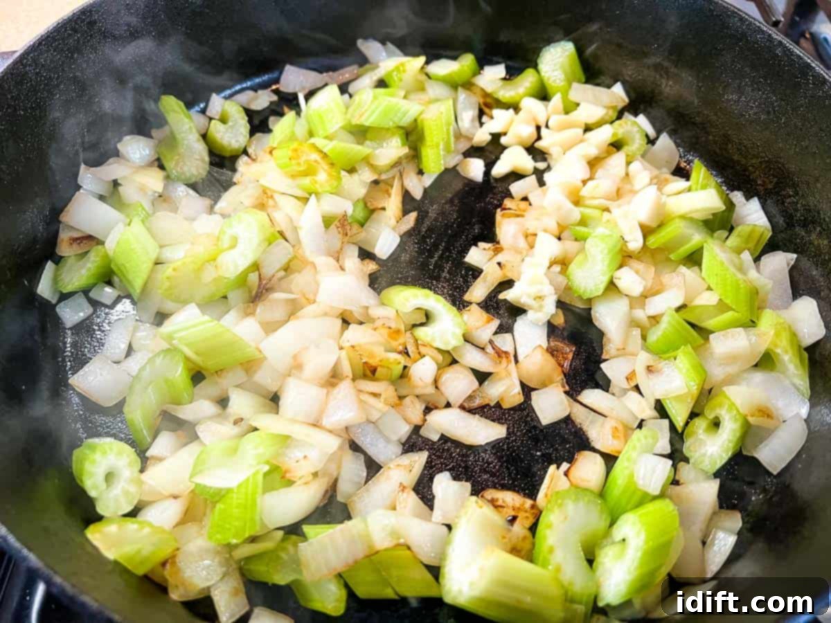 Hearty Smokehouse Beef Stew 8 Diced onions, celery, and garlic sizzling in a skillet with butter and oil, forming the aromatic base of the stew.