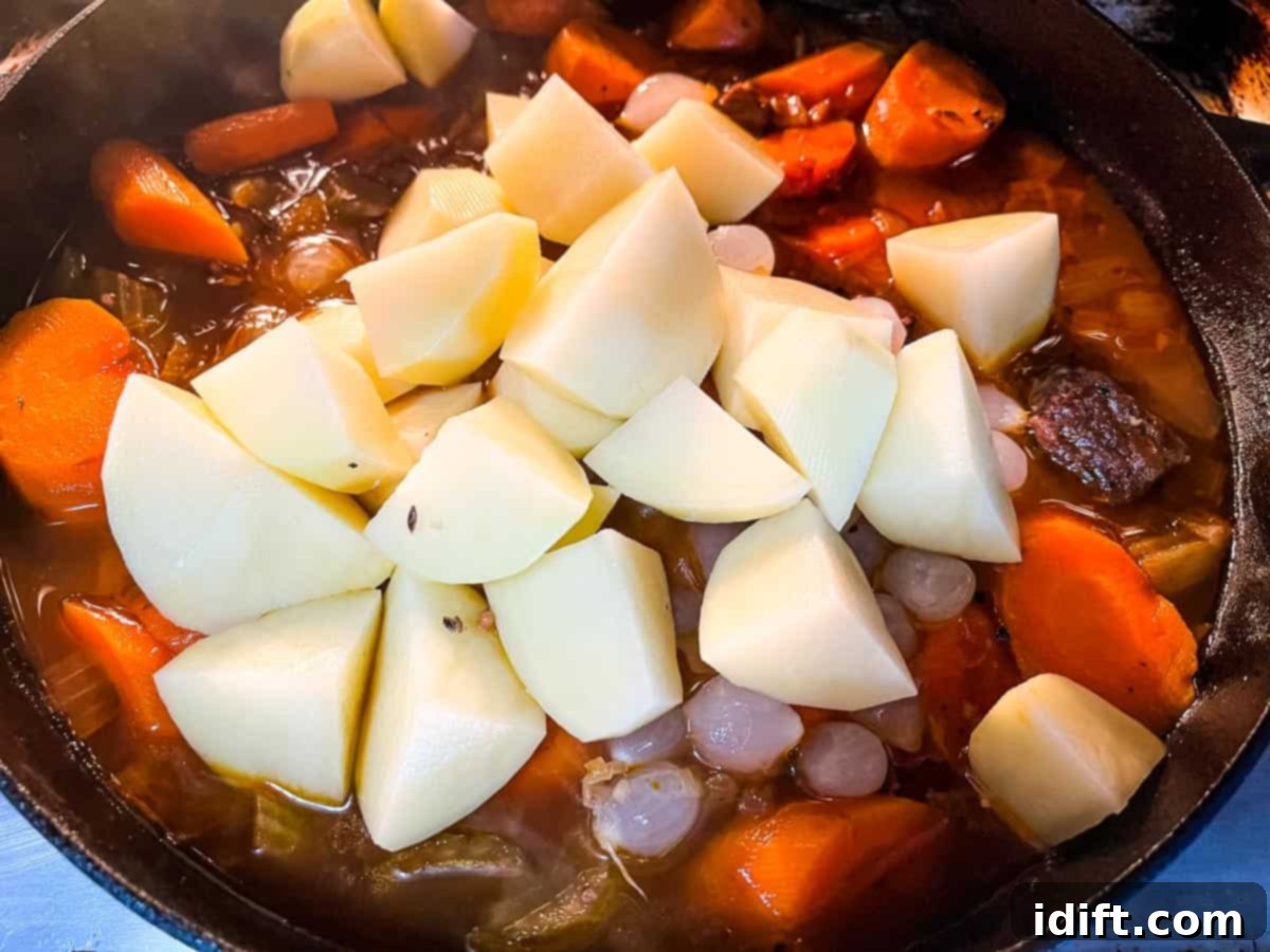 Hearty Smokehouse Beef Stew 10 Hearty chunks of potatoes and carrots added to the simmering stew in a cast iron pot, awaiting further smoking for perfect tenderness.