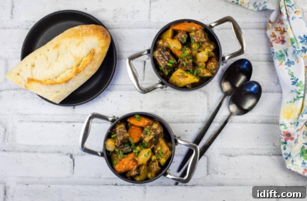 Hearty Smokehouse Beef Stew 3 A top-down view of two rustic black bowls brimming with Smoked Beef Stew, accompanied by slices of crusty bread, inviting a comforting meal.
