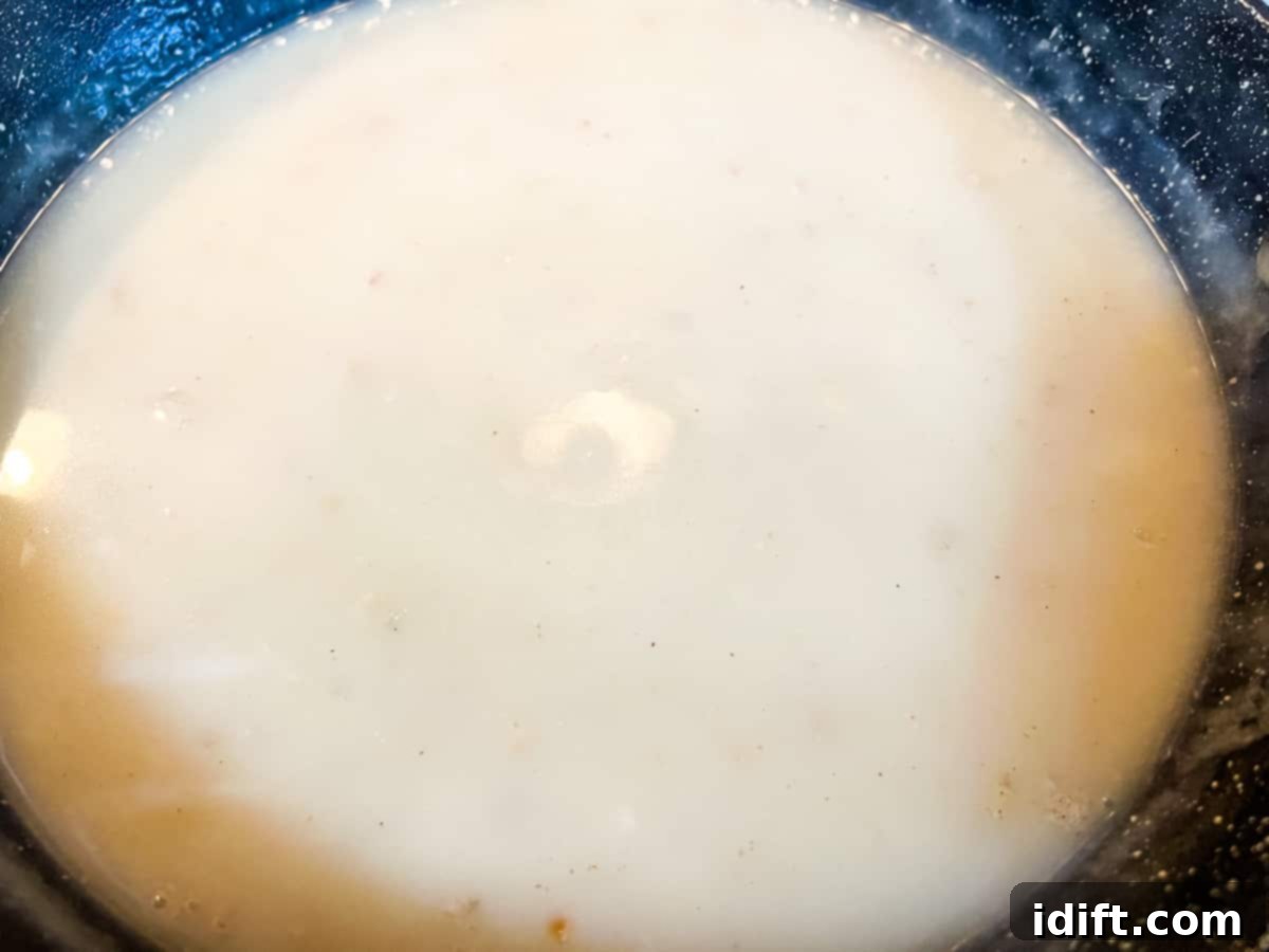 Fiery Crumb Carrot Bake 9 Chicken broth being whisked into the flour and shallot mixture, which is thickening into a sauce.