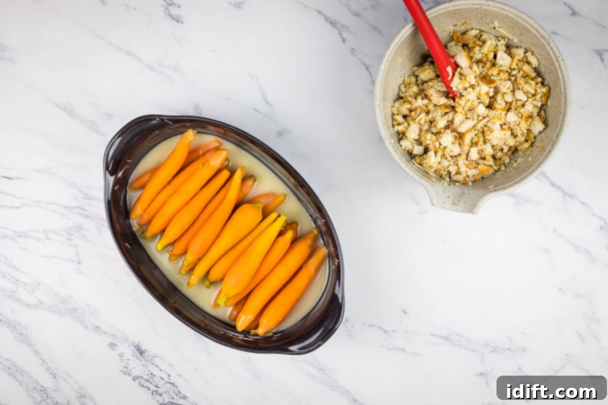 Fiery Breadcrumb Carrot Gratin 10 Parboiled carrots arranged in a baking dish, with the creamy sauce poured over them, ready for the topping.