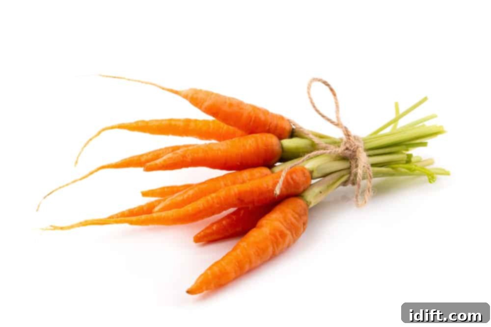 Fiery Crumb Carrot Bake 4 A vibrant display of fresh, young baby carrots with their green tops still on, artfully arranged on a white background.