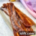 Millionaire's Bacon 11 Smoked candied bacon on a plate with maple syrup in the background.