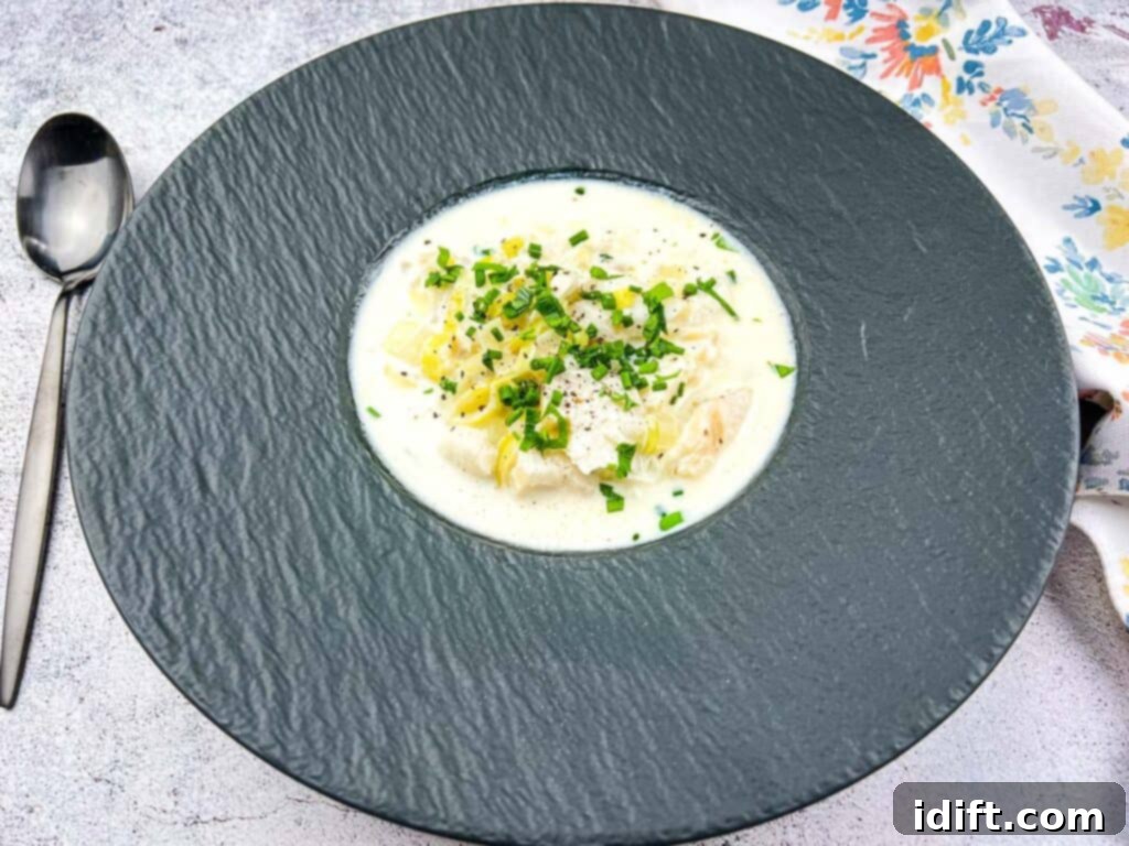 A single black bowl of Cullen Skink soup, garnished with fresh herbs, against a rustic background.