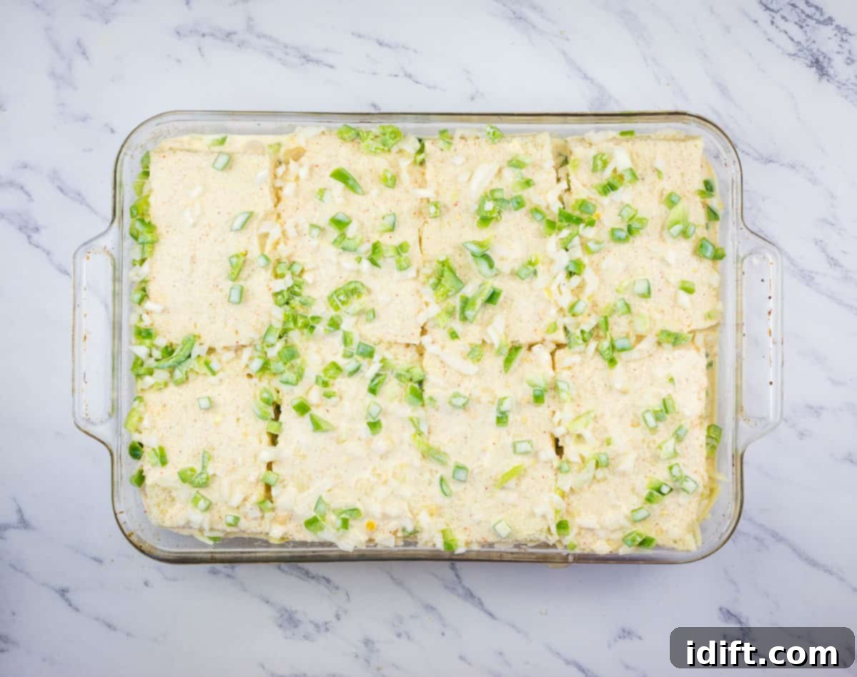 The prepared egg custard being poured over the layers of bread, meat, and cheese.