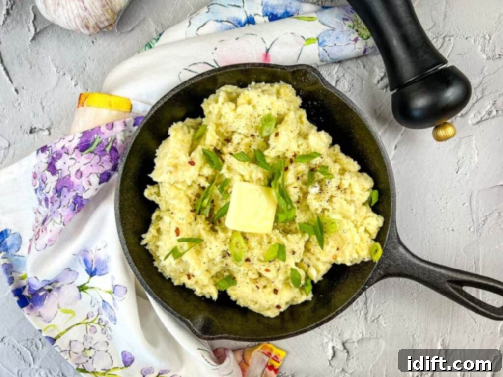 A black skillet filled with creamy, smoked mashed potatoes, garnished with fresh herbs, ready to be served.
