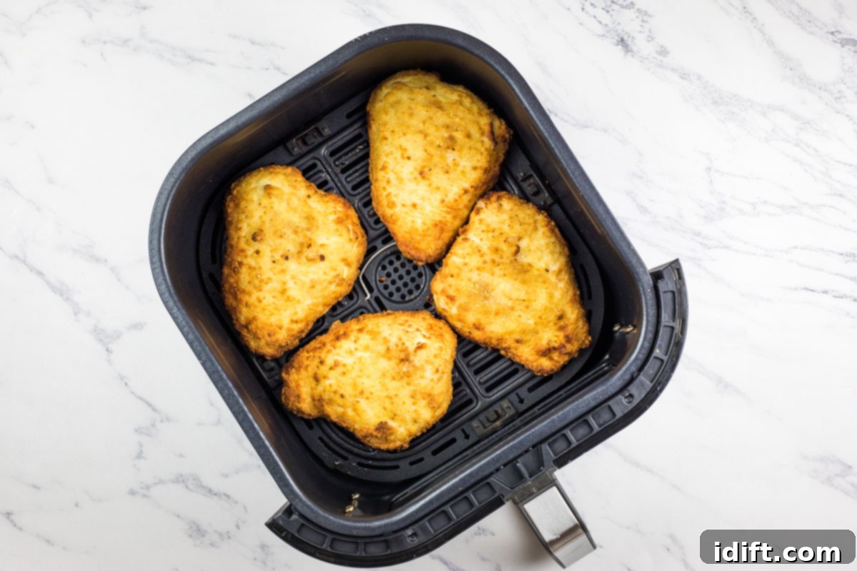 Frozen chicken cutlets neatly arranged in a preheated air fryer basket, ready for cooking.