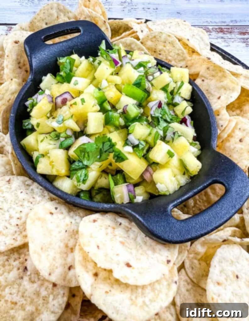 Lone Star Pineapple Salsa 2 Freshly made Texas-style Pineapple Salsa in a black bowl surrounded by crispy tortilla chips, ready for dipping.