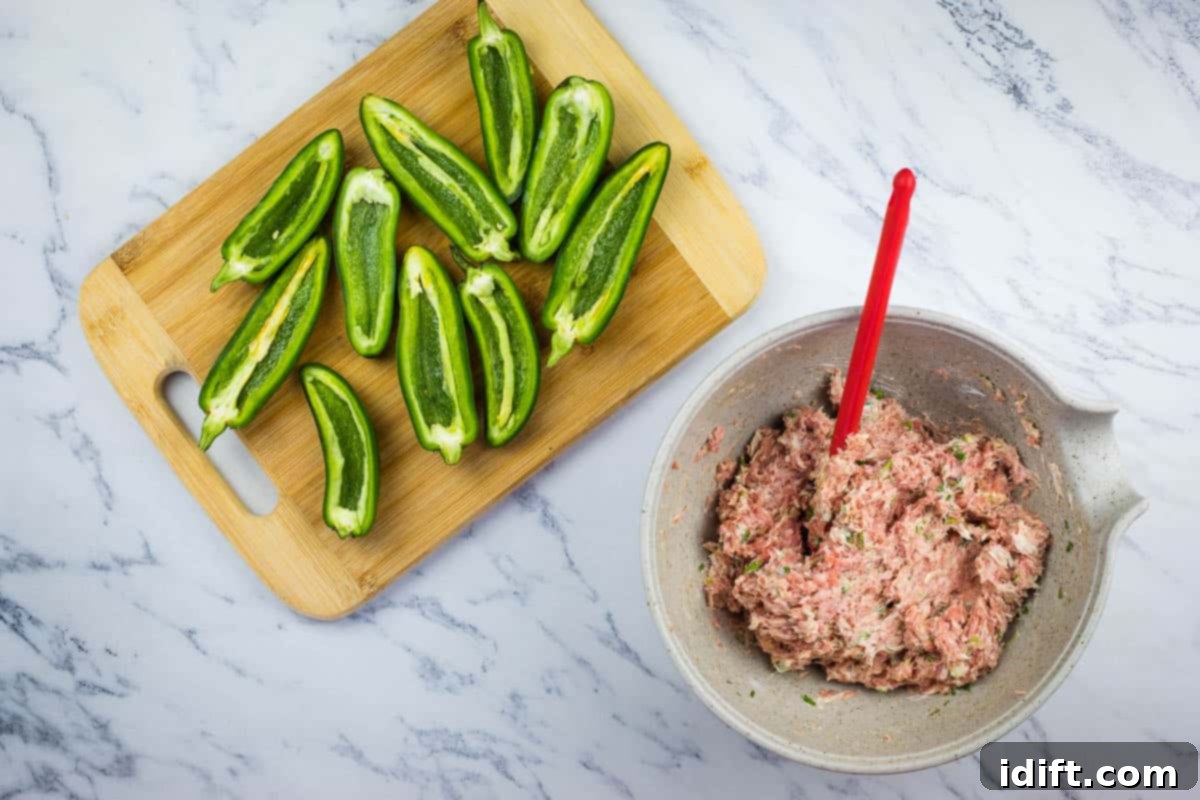 Cleaned and deseeded jalapeno halves neatly arranged on a cutting board, awaiting their savory pork filling.
