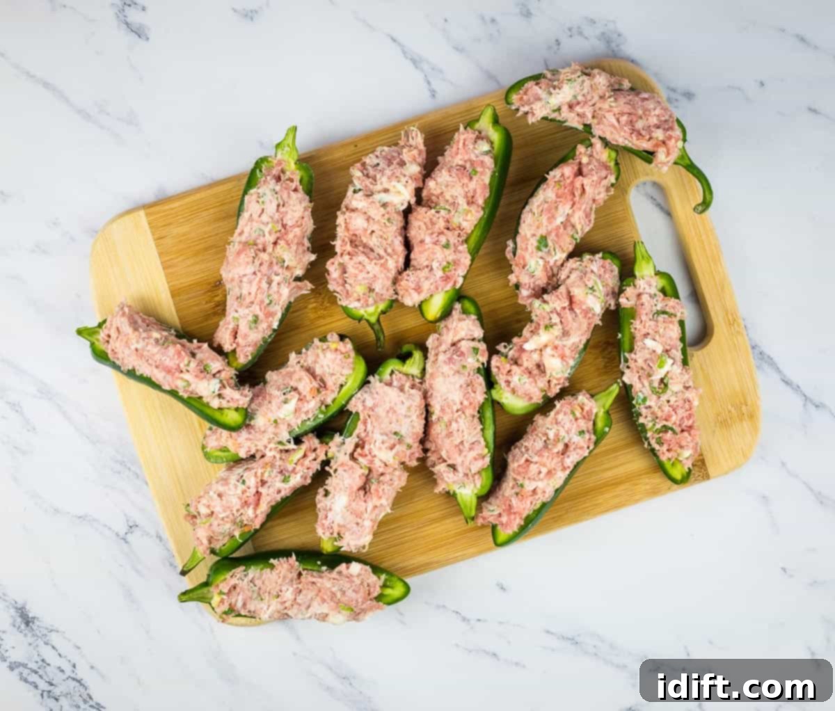 Jalapeno halves generously stuffed with the savory pork filling, showcasing their readiness for the bacon wrap.