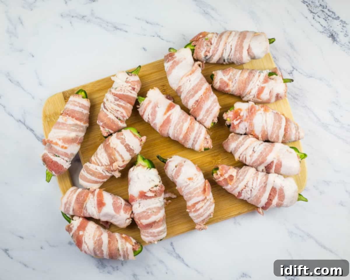 Bacon-wrapped jalapeno poppers neatly arranged on a wire rack, perfectly prepared and ready to go into the smoker.