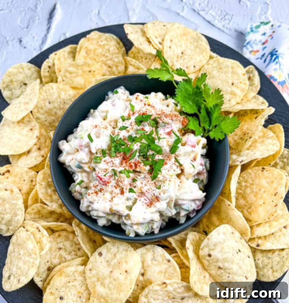 A beautifully presented cold corn dip in a sleek black bowl, surrounded by crispy tortilla chips, inviting you to grab a bite.