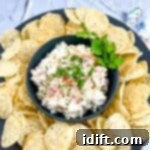 Cold corn dip in a black bowl with tortilla chips around it.