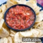 Food processor salsa in a black dish surrounded by tortilla chips.