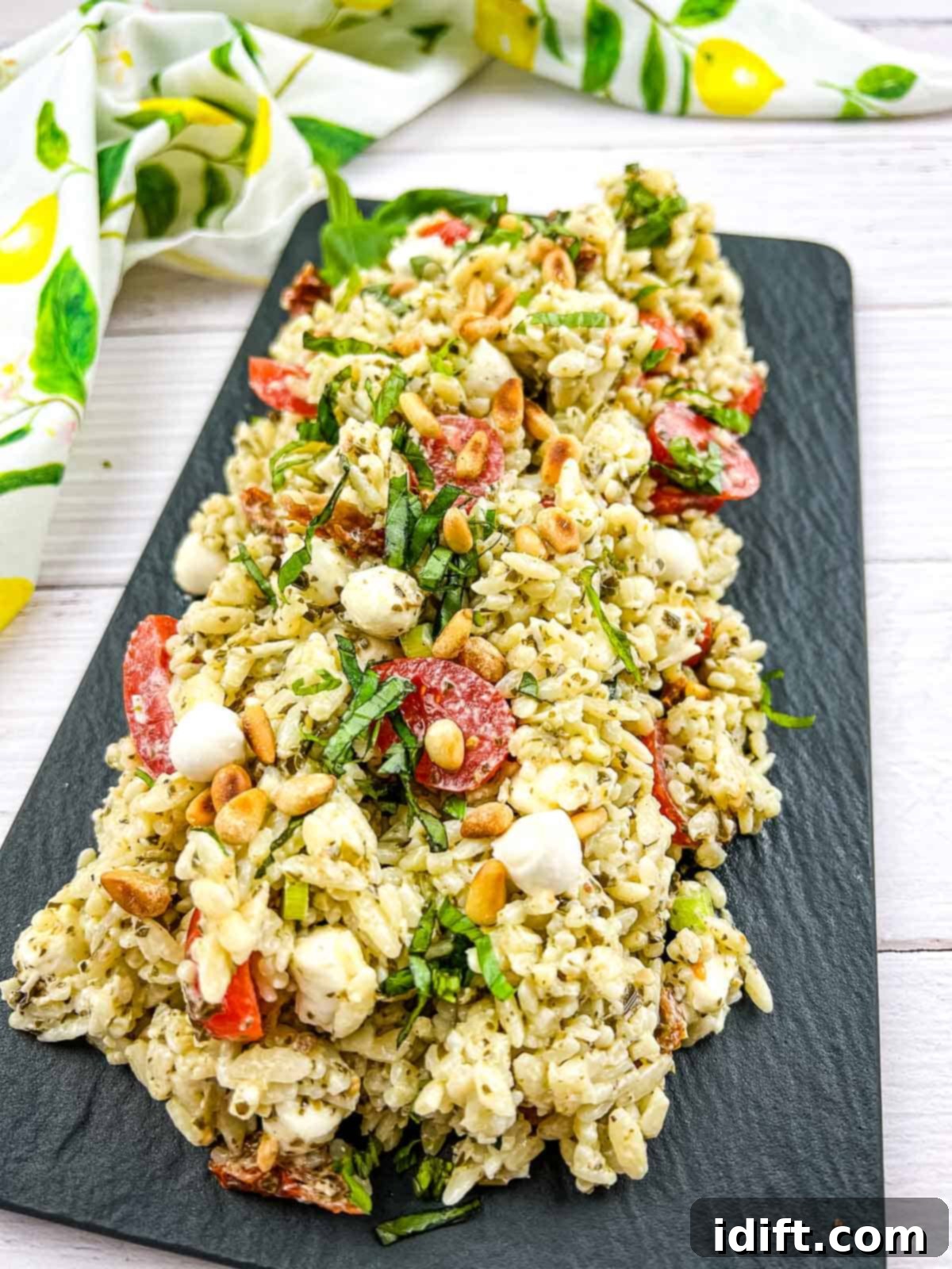 The finished Pesto Orzo Salad beautifully presented on a black serving dish, ready to be enjoyed.