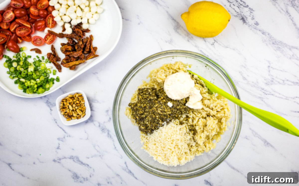Mixing the cooked orzo pasta with the creamy dressing ingredients in a large bowl.