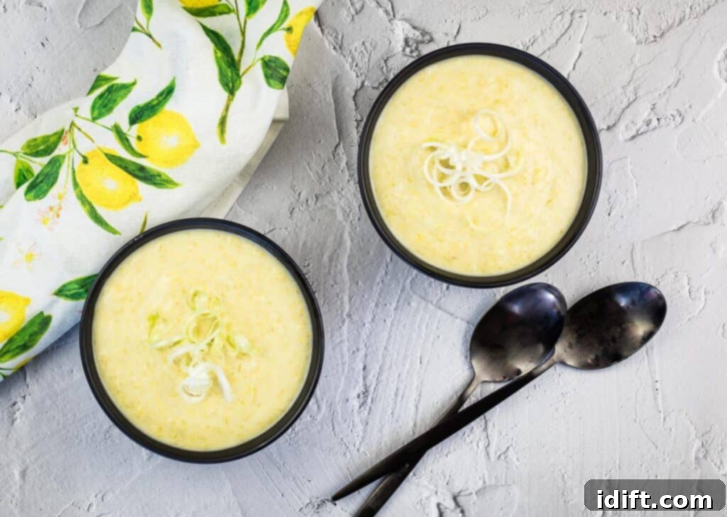 A top-down shot of two bowls of Cream of Leek and Green Garlic Soup.