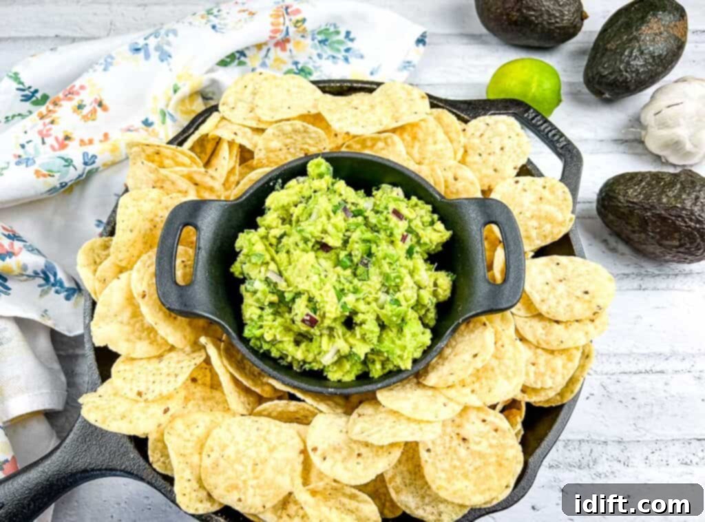 Next-Level Taco Bar Ideas for Your Tuesday Feast 5 A vibrant bowl of fresh guacamole, surrounded by crispy tortilla chips on a dark wooden surface.