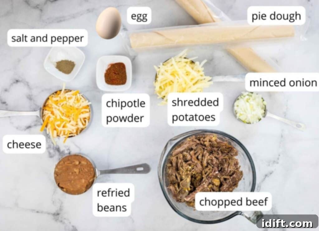 A neatly arranged collection of ingredients for air fryer beef empanadas on a kitchen counter, including bowls of shredded beef, cheese, potatoes, refried beans, onions, seasonings, pie dough, and an egg.