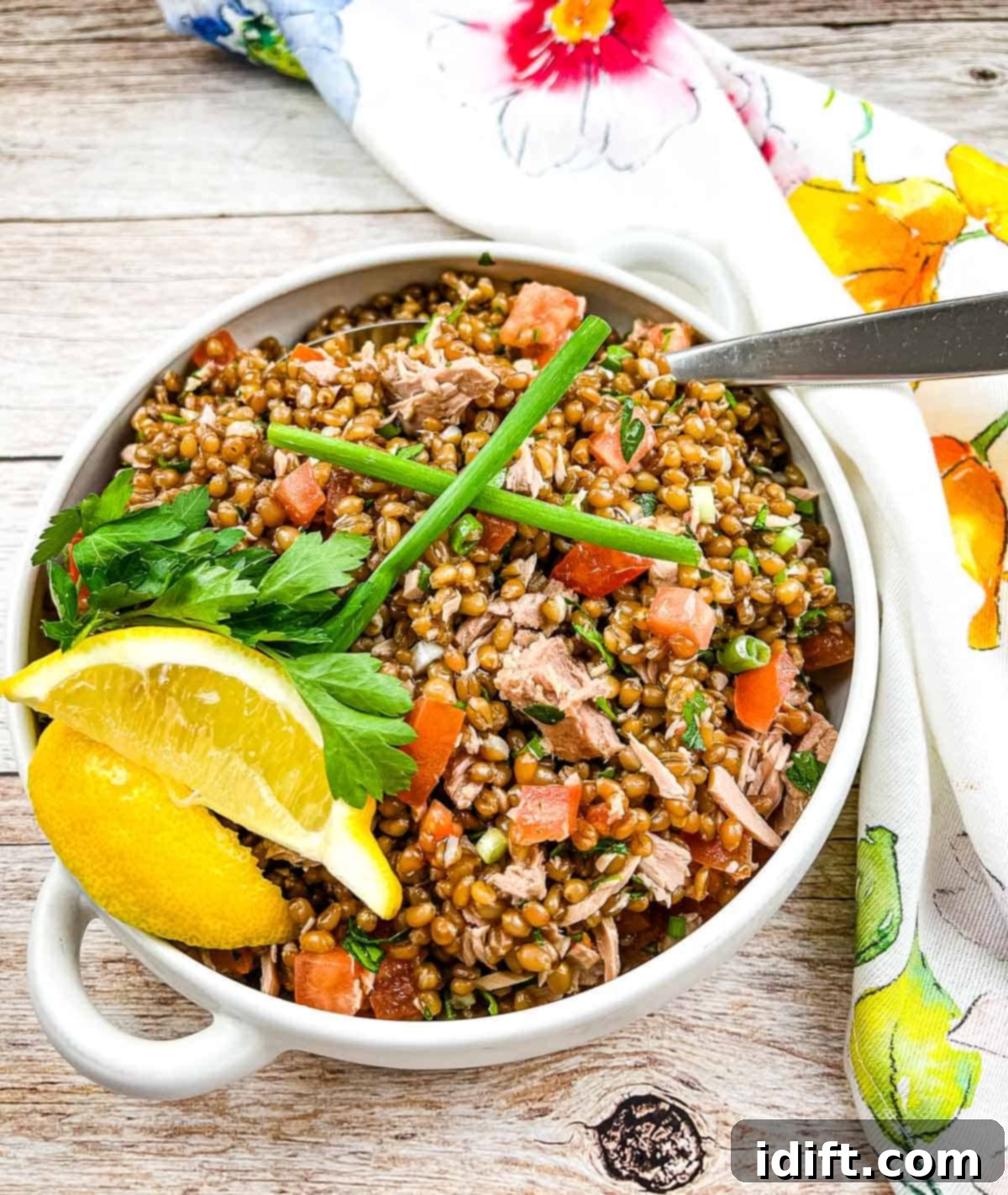 A horizontal image of the finished Wheat Berry Salad with Tuna and Tomatoes, plated and garnished.