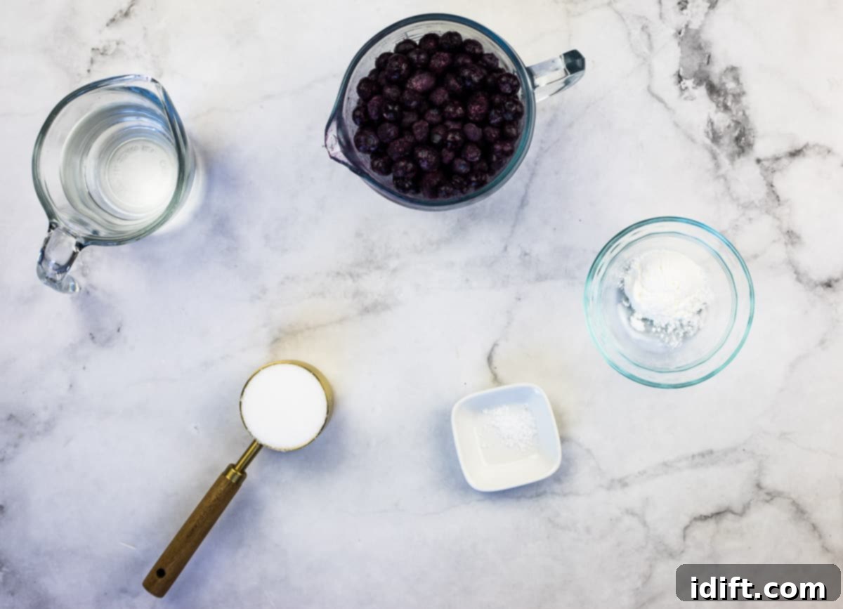 Ingredients for homemade blueberry sauce, including a bowl of frozen blueberries, water, sugar, cornstarch, and salt, arranged on a surface.