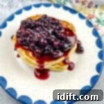 A stack of Blackstone Buttermilk pancakes with blueberry syrup on a plate.