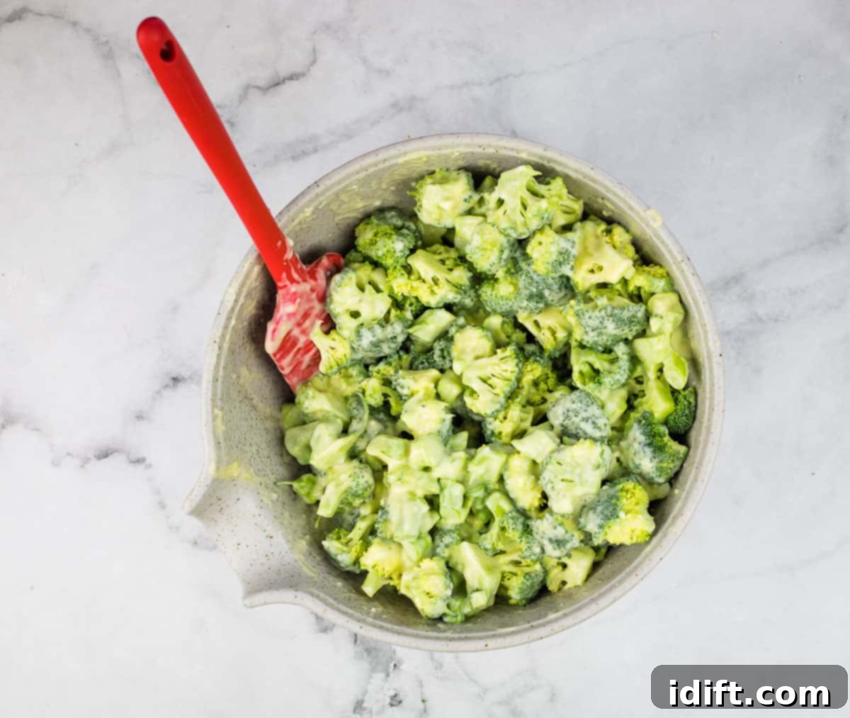 Vibrant Broccoli Salad with Zesty Orange and Smoky Bacon Crunch 8 Fresh broccoli florets being tossed evenly with the rich, creamy dressing in a large bowl, ready for marination.