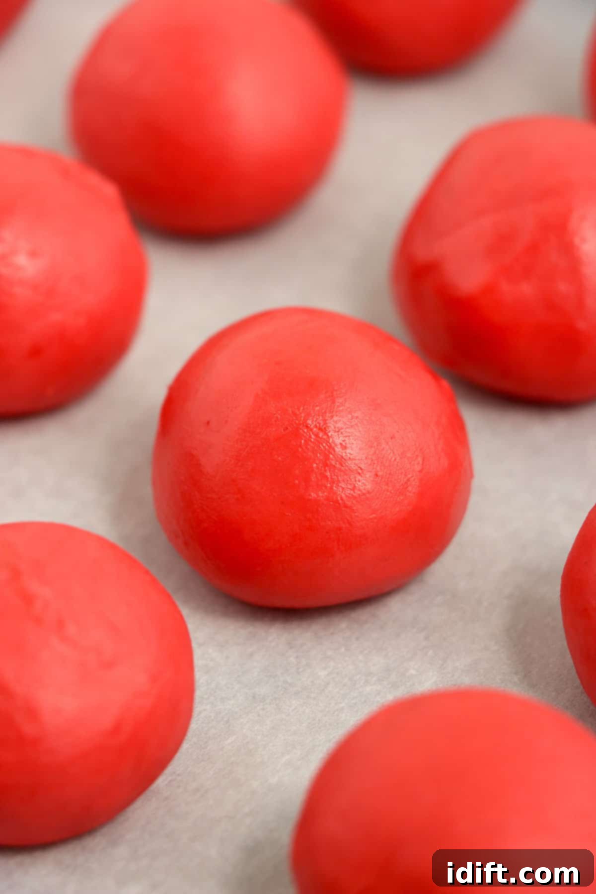 Several rolled red velvet truffles arranged on a sheet pan lined with parchment paper.