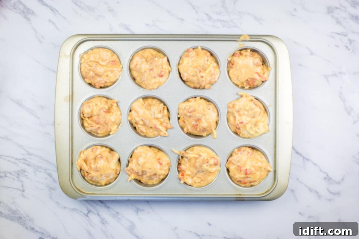 Savory Pizza Cups 10 A muffin pan filled with pizza muffin batter, ready to be placed into the oven for baking.