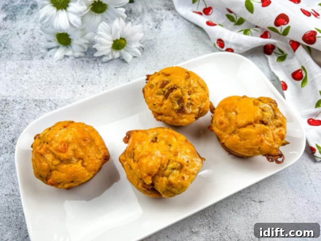 Savory Pizza Cups 3 A top-down horizontal shot showcasing four delicious pizza muffins on a pristine white plate, garnished with fresh herbs.