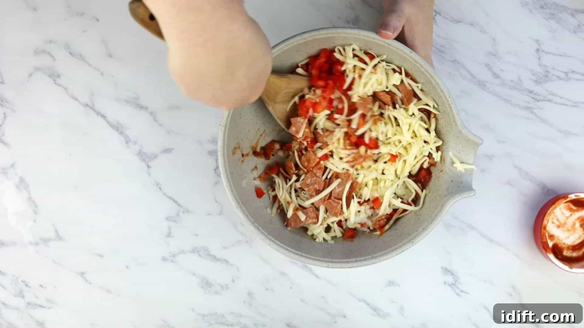 Savory Pizza Cups 6 A bowl filled with mixed pizza ingredients including chopped pepperoni, cheese, and vegetables, ready to be combined with batter.