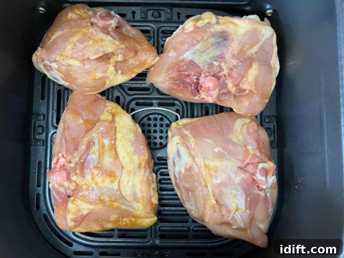 Chicken skin side down in an air fryer basket.