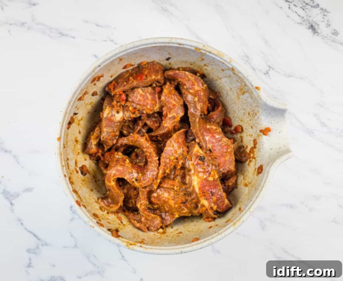 Sizzling Steak Skewers with Zesty Mojo Rojo 8 Thin strips of steak marinating in a generous coating of red Mojo Rojo sauce in a glass bowl.