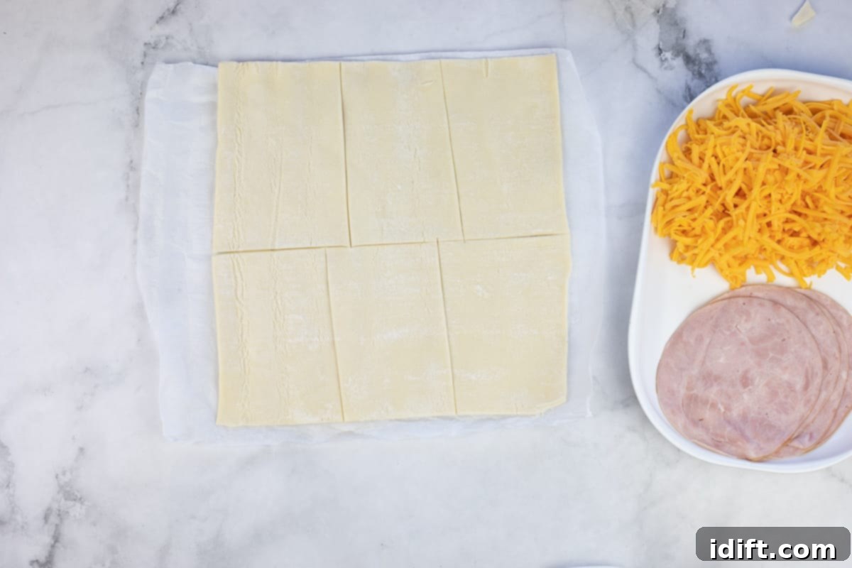 Puff pastry rolled out and cut into squares on a kitchen counter.