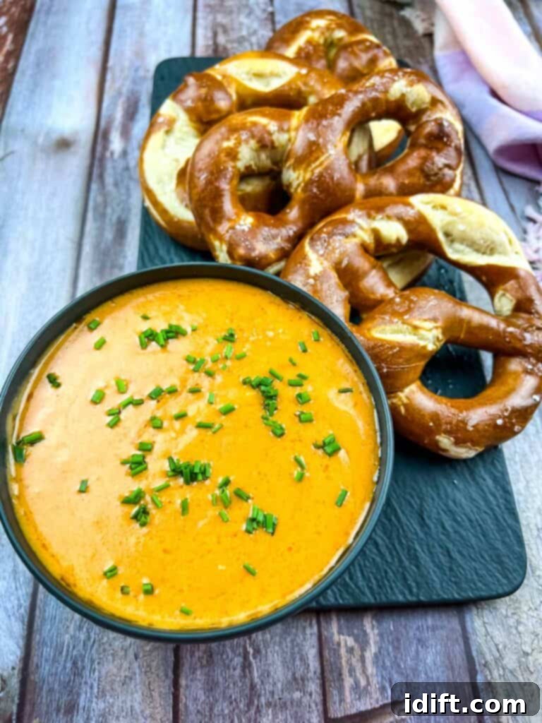 Hearty Guinness Beer Cheese Dip 2 Guinness Cheese Dip in a black bowl with pretzels nearby.