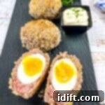 Crispy Baked Scotch Eggs 14 Cut open Scotch Eggs and whole Scotch Eggs on a black platter.