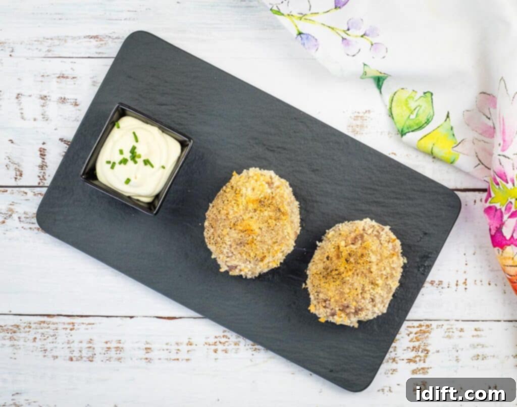 Crispy Baked Scotch Eggs 5 a top-down shot of 2 baked scotch eggs on a black plate.