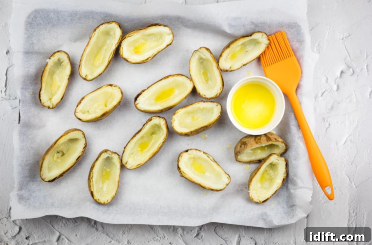 Potato skins on a baking sheet brushed with butter.